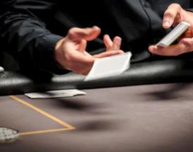 Dealer dá carta em mesa de poker